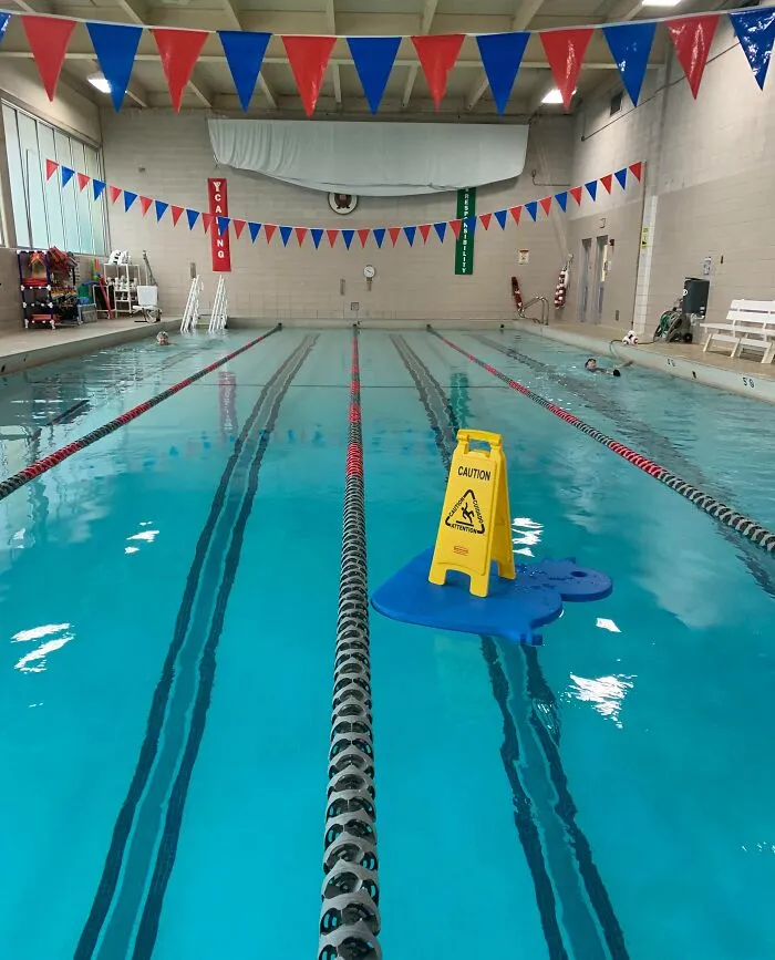 Put A “Caution Wet Floor” Sign Atop Of A Giant Floaty Mat. Swimmers & Colleagues Got A Kick Out Of It