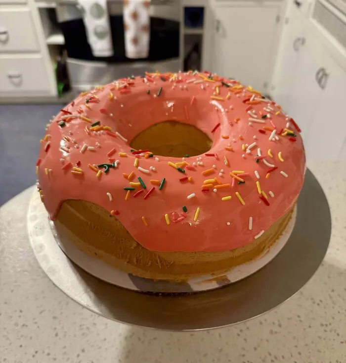 Rosca de repostería con glaseado rosa y chispas de colores, mostrando creatividad y técnica avanzada en repostería.