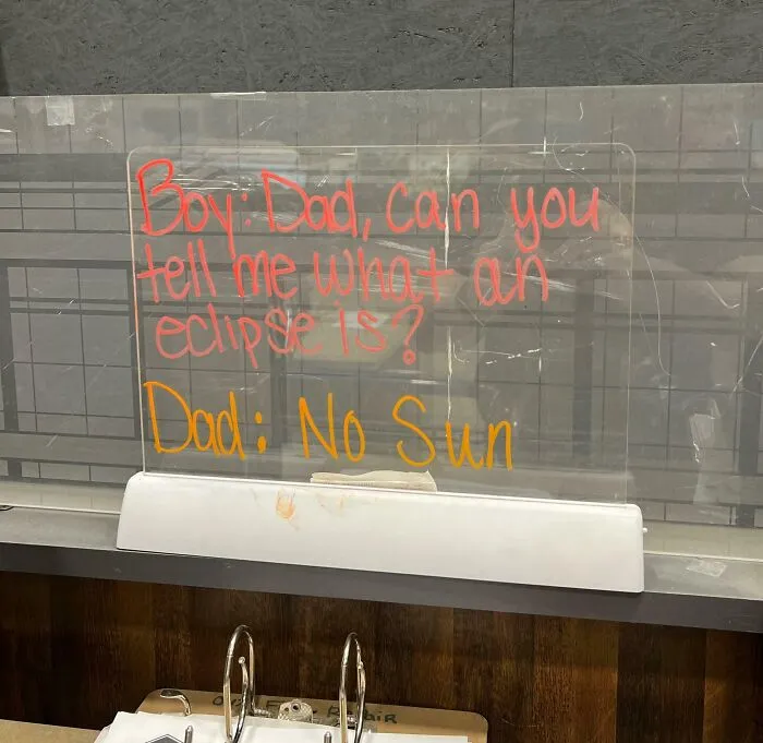 A humorous note about an eclipse written on a transparent board by a witty coworker.