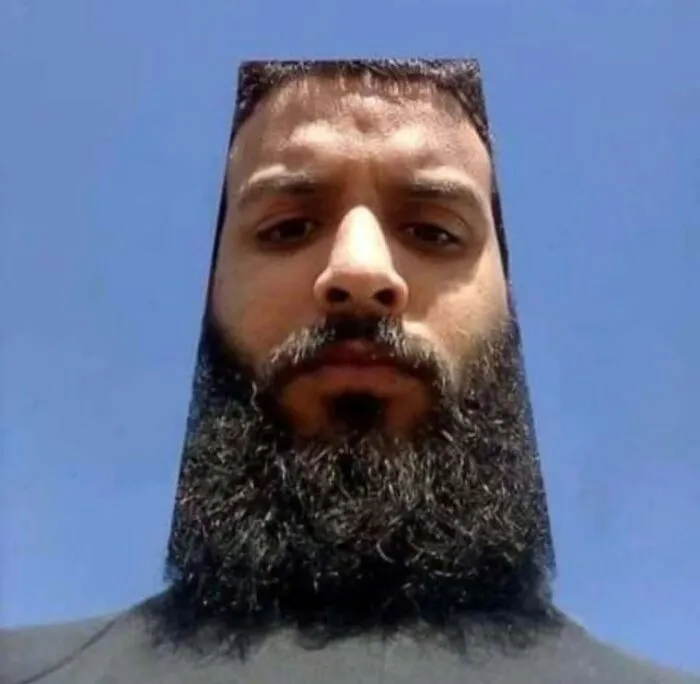 Hombre con barba cuadrada perfecta que crea una imagen maldita y difícil de explicar contra un cielo azul.