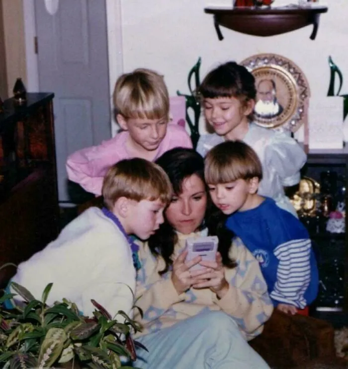 Mother Helping Her Son Through A Tough Level In Super Mario Land On Gameboy From 1989