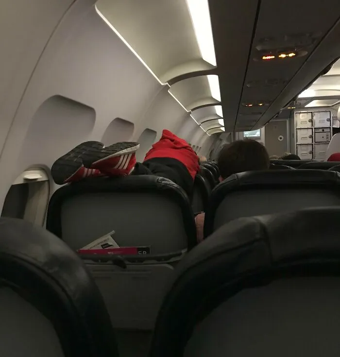 Pasajero acostado con los pies sobre asiento en avión, ignorando normas básicas de educación y respeto.