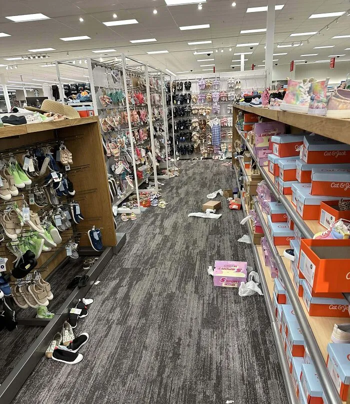 Pasillo de tienda con zapatos desordenados y basura en el suelo, mostrando ignorancia de normas básicas de educación.