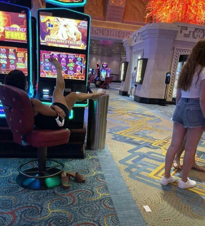 Mujer ignorante en casino con pies sobre mesa y comportamiento que viola normas básicas de educación y respeto.