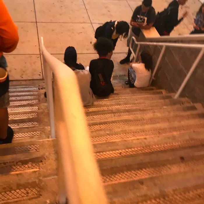 Personas ignorantes sentadas en escaleras públicas sin respetar normas básicas de educación ni espacio personal.