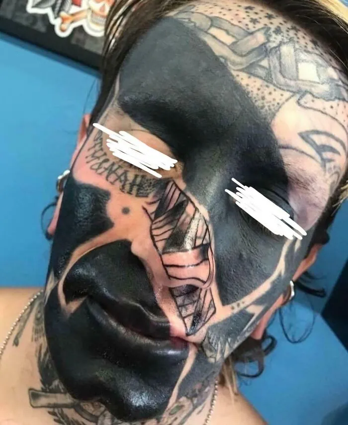 Tatuaje facial en negro intenso cubriendo gran parte del rostro, ejemplo de mala elección en tatuajes visibles.