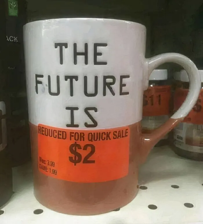 A mug with "The Future Is" on it, covered with a $2 sale sticker; reflects funny meme humor.