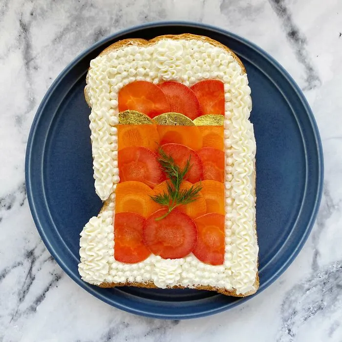 Creative toast design by Japanese artist with intricate patterns, featuring colorful toppings on a blue plate.