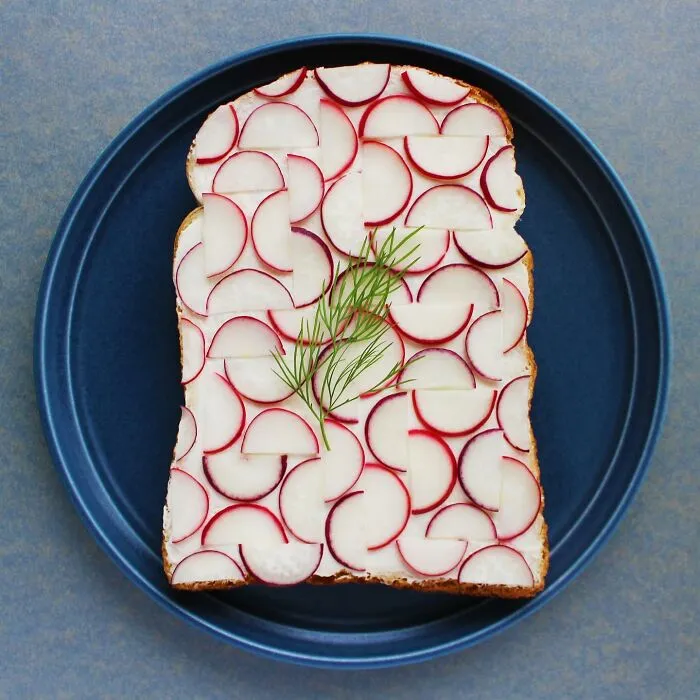 Creative toast design featuring radish slices and dill on a blue plate by a Japanese artist.