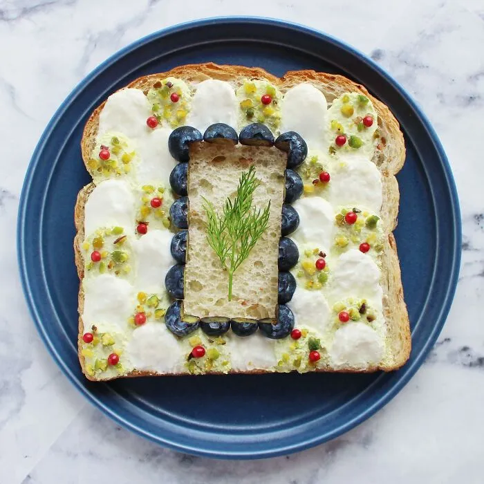 Creative toast design with blueberries and dill on a blue plate.