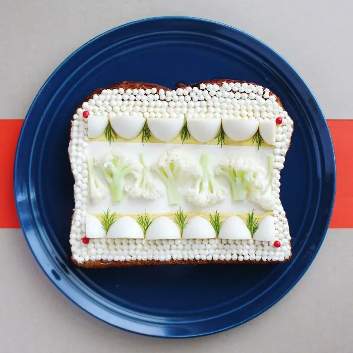 Creative toast design with cauliflower and egg patterns on a blue plate.