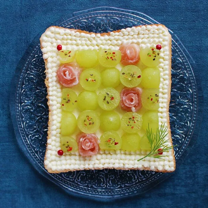 Creative toast design by Japanese artist with melon balls and decorative elements on a clear plate.