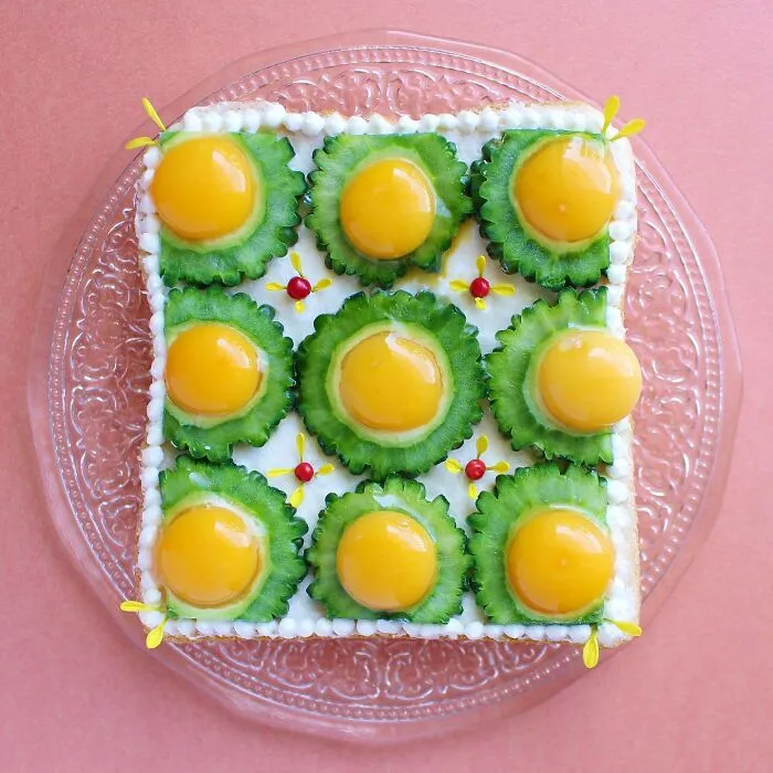 Creative toast design featuring vibrant green and yellow toppings arranged symmetrically on a decorative clear plate.