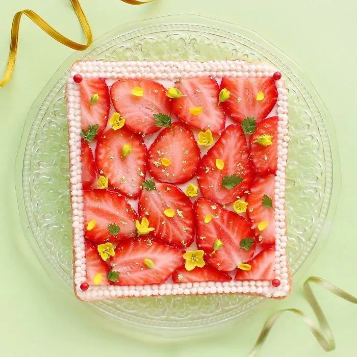 Creative toast design featuring strawberries and flowers on a glass plate.