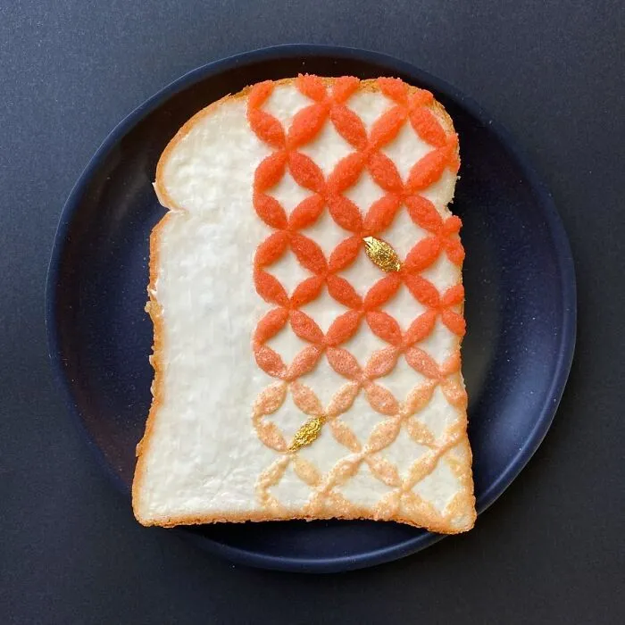 Creative toast design with orange geometric patterns by Japanese artist on a black plate.