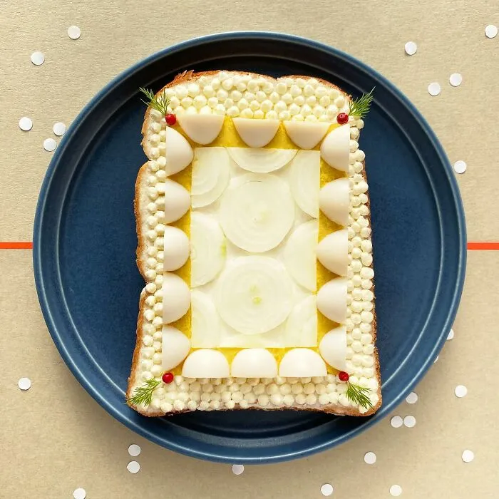 Creative toast design by Japanese artist, featuring artistic patterns with sliced eggs and onions on a blue plate.