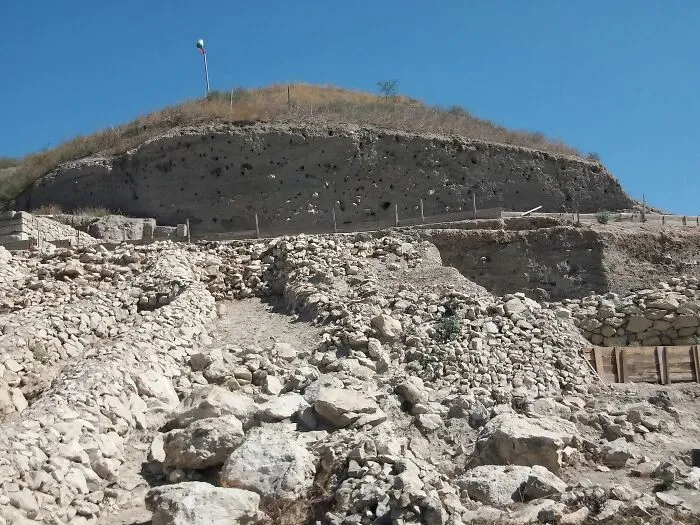 Ancient man-made stone structures and ruins on a hillside under clear blue sky showcasing historic architecture.