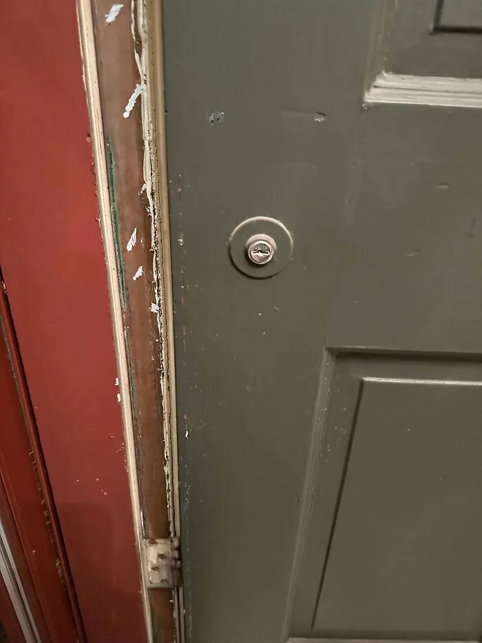 Old green door with a unique round lock mechanism and worn door frame, one of the mystery objects recognized online.