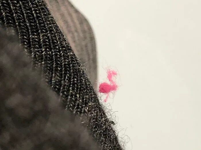 Peluche rosado con forma de flamenco en una prenda tejida negra mostrando una coincidencia increíble.
