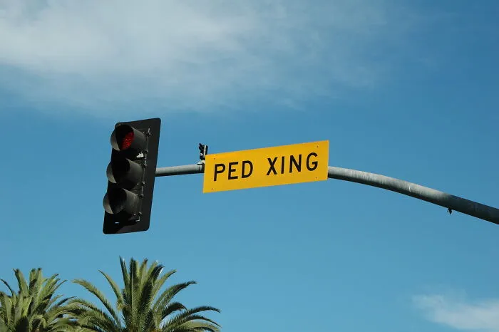 Traffic light with red signal and pedestrian crossing sign under a clear sky, illustrating obvious things noticed recently.
