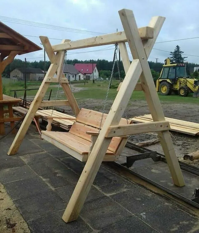 Wooden outdoor swing made of natural wood with a sturdy frame, showcasing creative woodworking ideas and craftsmanship.