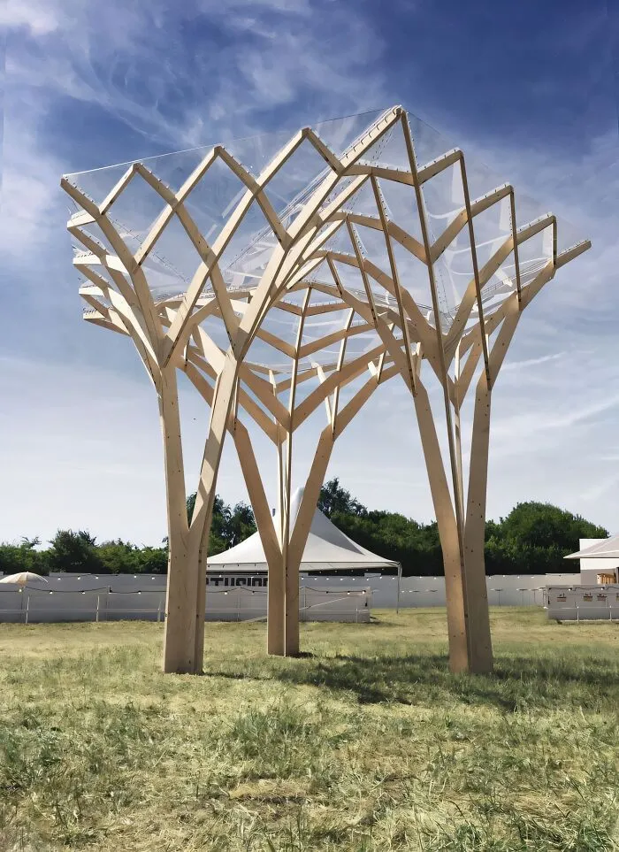 Large wooden sculpture with intricate geometric design, showcasing impressive woodworking ideas in an outdoor grassy area.