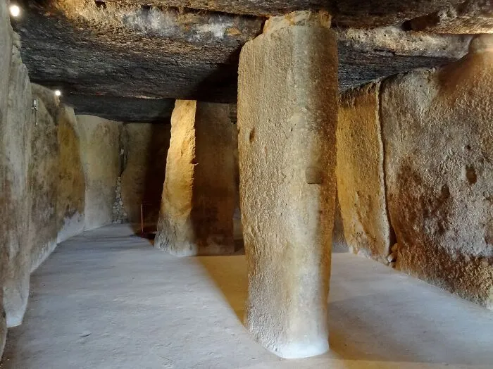 Interior view of an ancient man-made structure with large stone pillars supporting the ceiling, highlighting historic architecture.