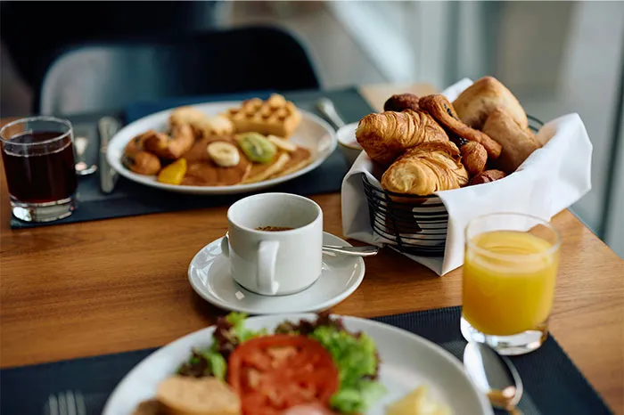 Breakfast table with croissants, coffee, juice, and fruit, reflecting money-saving tips from the Great Recession.