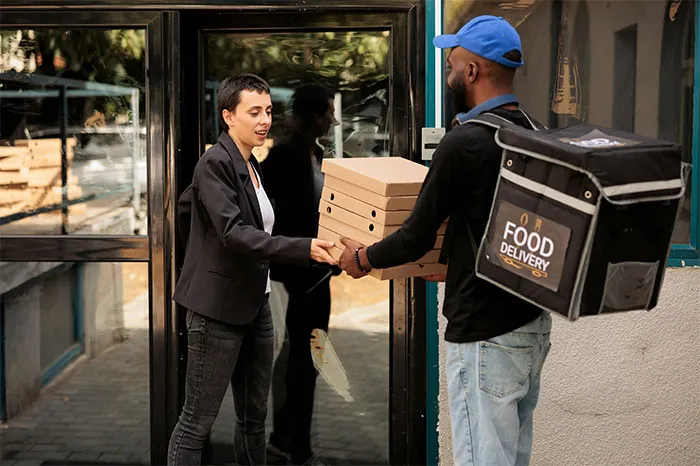 Person receiving food delivery boxes from courier, showcasing a practical money saving tip.