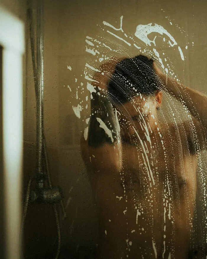 Person showering behind a steamy glass door, illustrating the allure of expensive weddings.