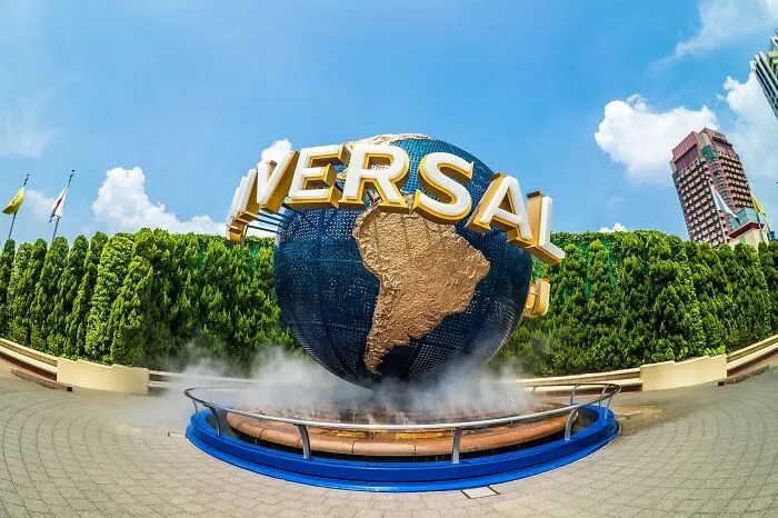 Universal globe monument surrounded by trees under a clear blue sky, highlighting tourist experiences.