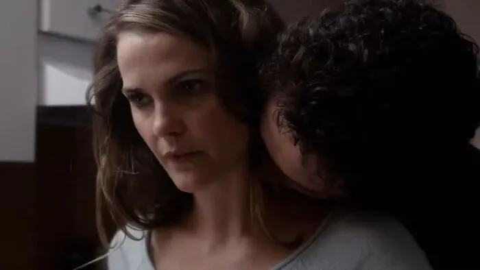 A dramatic scene from a 10/10 show, featuring a woman looking worried with a man close behind her.