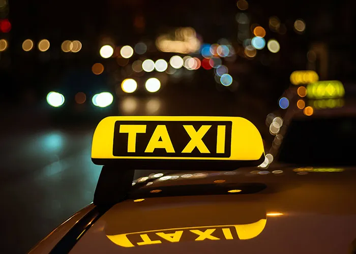 Luz de taxi iluminada de noche, contexto urbano. Experiencia callejera que sugiere alejarse de situaciones potencialmente tensas.