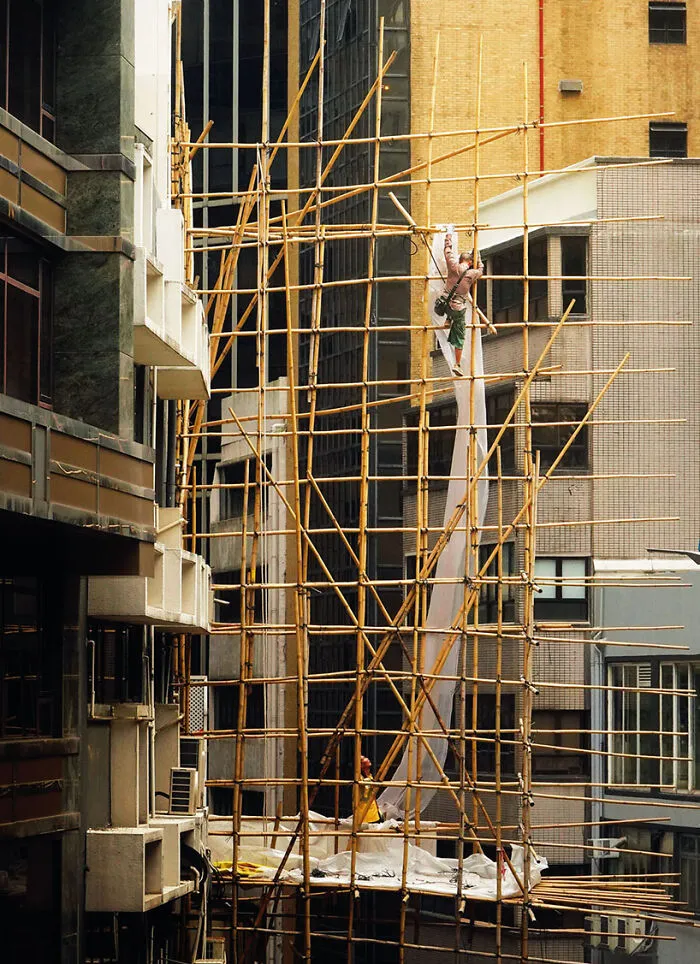 Ascending Bamboos, 2023 - A Scaffolder Is Bringing Up The Fabric That Will Wrap The Bamboo Scaffolding He Did