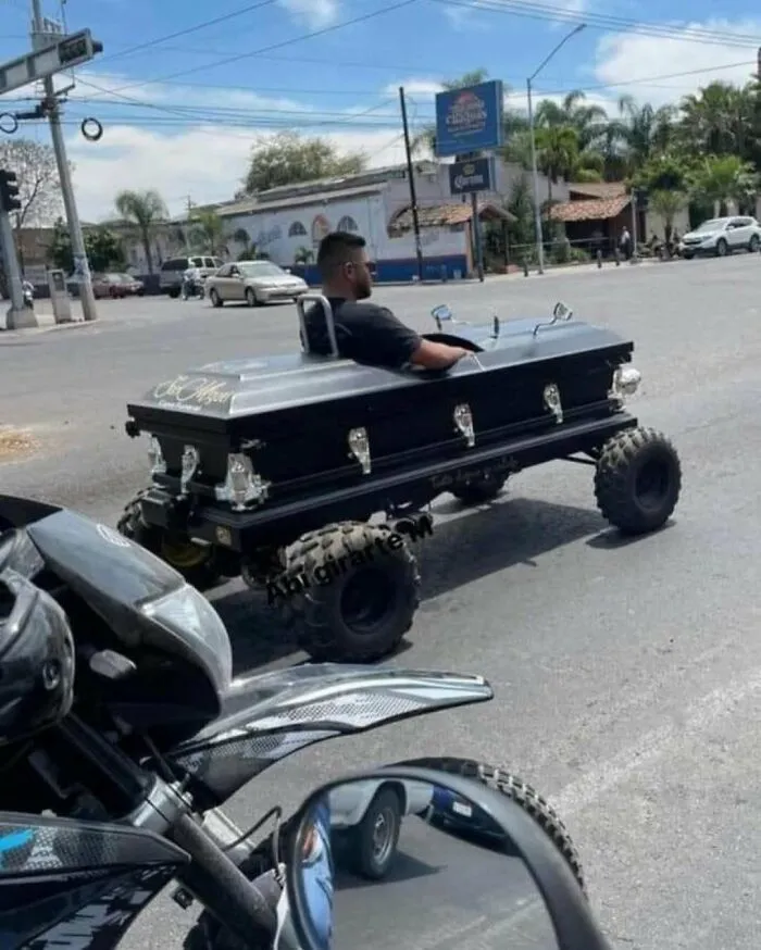 Hombre conduciendo un vehículo modificado con forma de ataúd en una calle vacía, imagen maldita inexplicable.