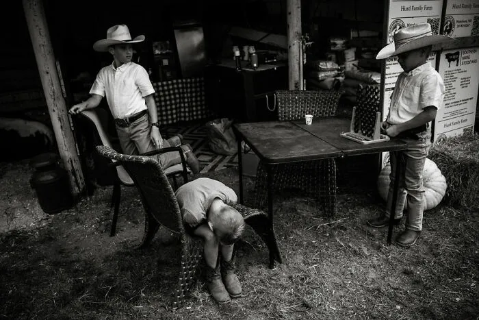 Three children in cowboy hats on a rural farm, illustrating intimate rural life in Maine.