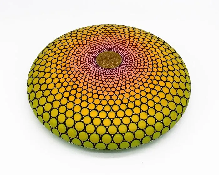 Colorful mandala design painted on a round stone with intricate patterns.
