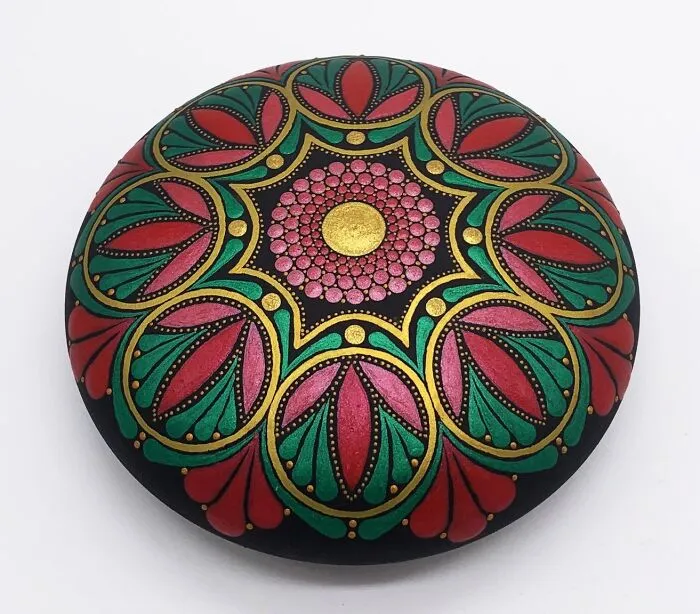 Beautiful mandala artwork painted on a stone with intricate patterns in red, green, and gold.