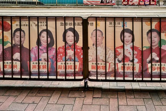 People on a poster appear behind a metal fence, creating a perfectly timed visual illusion.