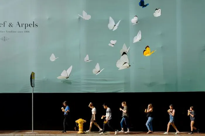 People walk past a wall with butterfly designs, creating a perfectly timed coincidence.
