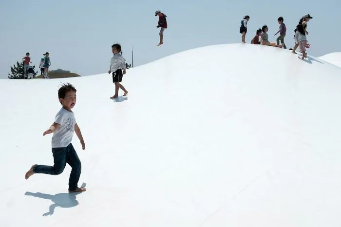 Children playing on a large, white inflatable surface under a clear sky, capturing a perfect coincidence.