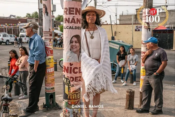 Woman standing beside a pole, creating a perfectly timed coincidence with the image on the poster behind her.