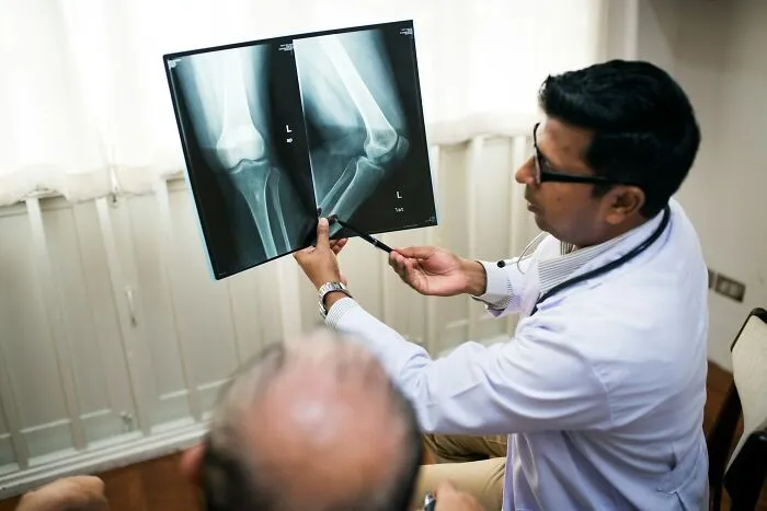Doctor examining disturbing X-ray images with patient in medical office.