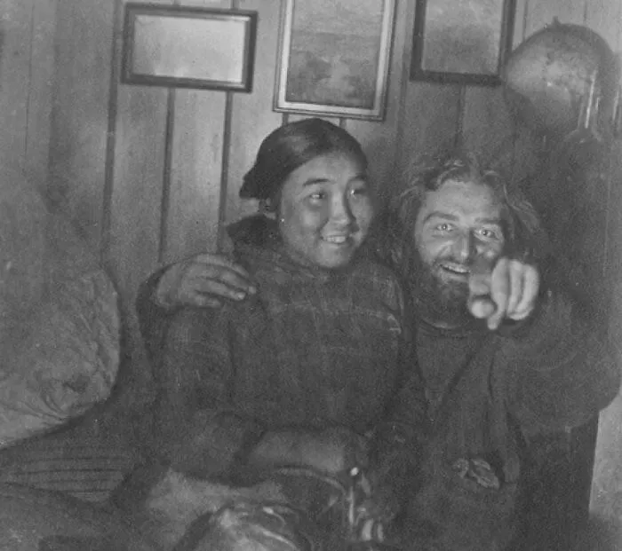 Two people sitting closely, with one pointing forward, evoking a scene from "Forbidden Stories."