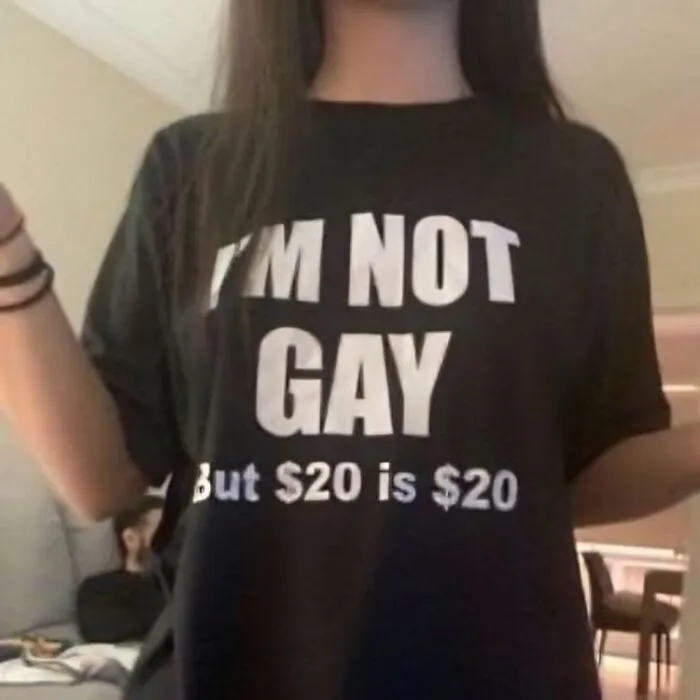 Persona con camiseta divertida y ridícula con texto en inglés, mostrando moda informal y humor en prendas públicas.