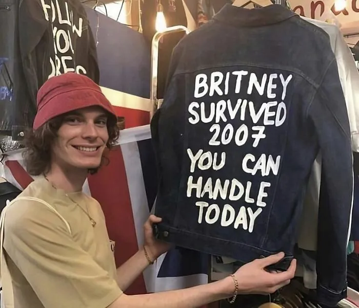 Joven sostiene una chaqueta con mensaje divertido, ejemplo de camisetas tan divertidas como ridículas para uso público.
