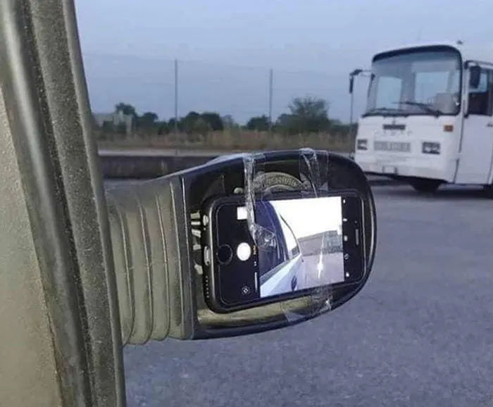 Espejo roto de coche reparado con un teléfono móvil pegado con cinta.