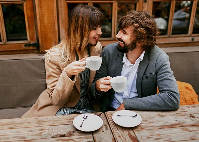 Couple enjoying coffee together at an outdoor café, smiling and engaged in conversation, reflecting on what they found.