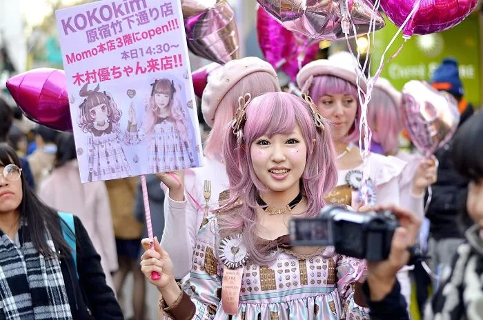 Young woman in a colorful outfit holds a sign on a bustling street, embodying tourist FOMO experiences.