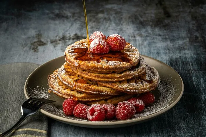Stack of pancakes with syrup and raspberries on a plate, highlighting an unpopular opinion on power naps.